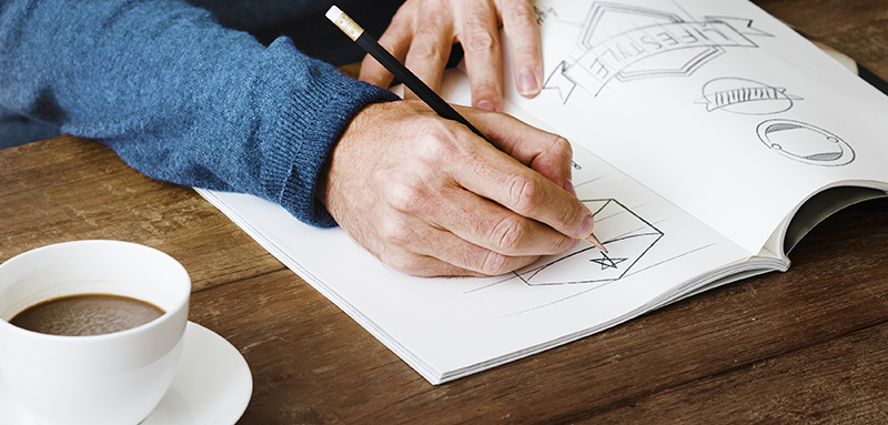 Un uomo che disegna uno sketch per il marchio del proprio cliente raggiungendo l obiettivo di design predefinito dal progetto iniziale