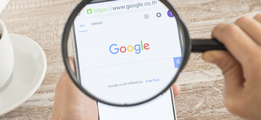 Lente di ingrandimento con focus sullo schermo di un telefono mobile con dettaglio sulla barra di ricerca di Google al fine di rappresentare visivamente le campagna Google ADS Search